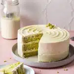 Vegan pistachio cake sliced on a table with pistachio crumbs