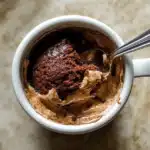 3 ingredient mug cake in a white mug topped with whipped cream, cocoa powder