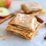 Homemade apple pop tarts stacked with cinnamon glaze on top and a flaky crust, filled with spiced apple filling.