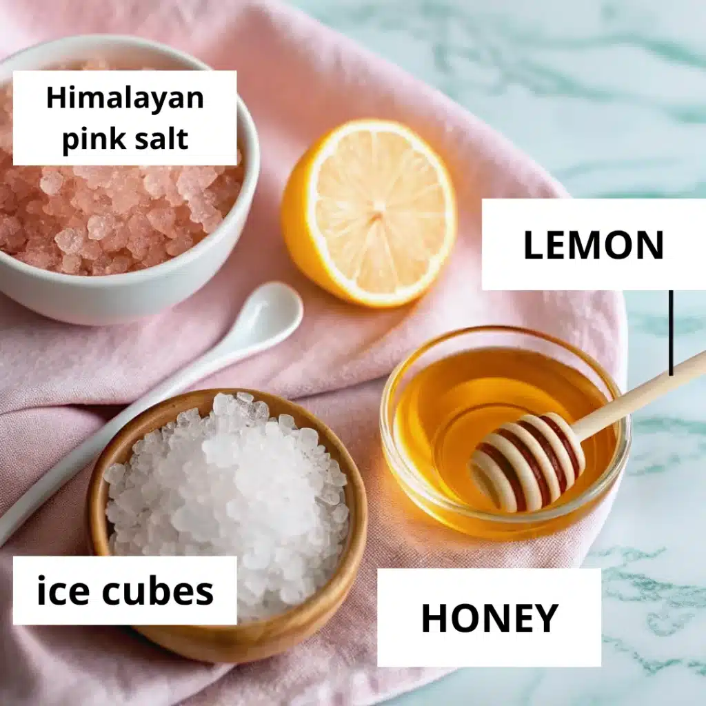 Himalayan pink salt, ice cubes, lemon, and honey arranged on a pink cloth with a white spoon and marble background