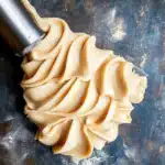 Maple frosting piped in swirls on a dark surface using a metal tip