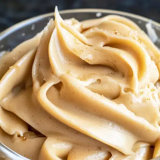 Close-up of creamy maple frosting with sugar crystals in a glass bowl