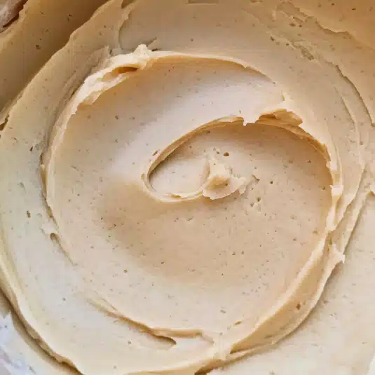 Close-up swirl of creamy peanut butter cream cheese frosting in a mixing bowl