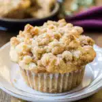 Freshly baked muffin with buttery streusel topping on a white plate