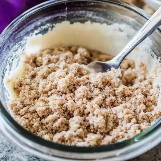 Unbaked brown sugar streusel topping mixture in a glass bowl with a spoon