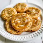 Soft and chewy caramel cookies drizzled with caramel sauce on a white plate